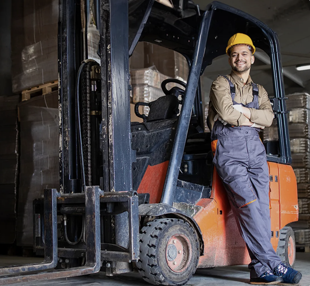 Staplerfahrer in Arbeitskleidung steht vor Gabelstapler im Lager – Personalvermittlung Staplerfahrer